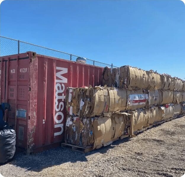 A pile of cardboard boxes next to a red container.