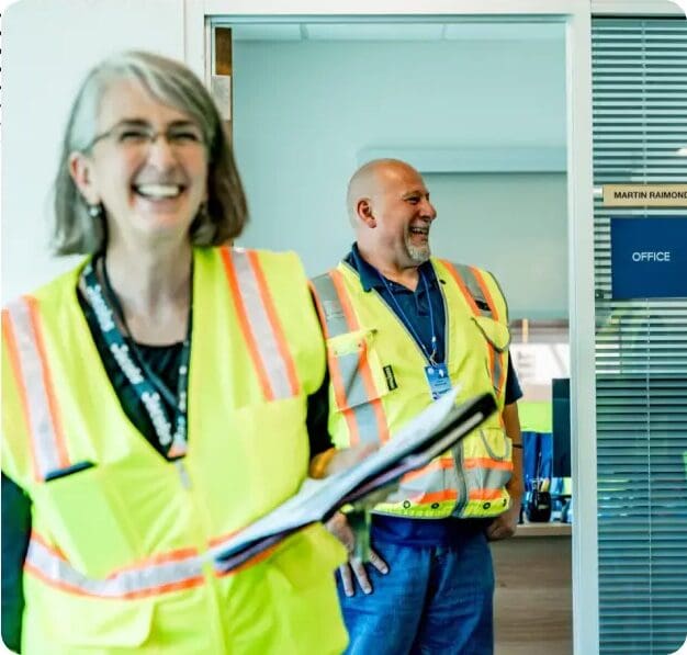 A woman in yellow vest holding a clipboard.